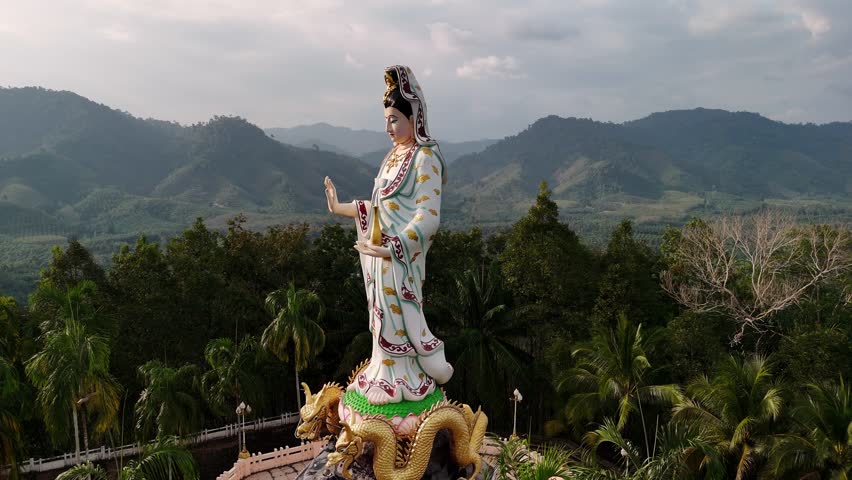 Aerial view of Guanyin statue standing mountain peak, viewing lush valley at wat bang riang temple, phang nga, Thailand landscape