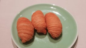 slow motion of close up of three pieces of Cantonese Hong Kong style dim sum deep fried baked puff pastries with shredded turnip on a green plate. Copy space on the right. - Powered by Shutterstock - Get 15% off with code: PIKWIZARD15