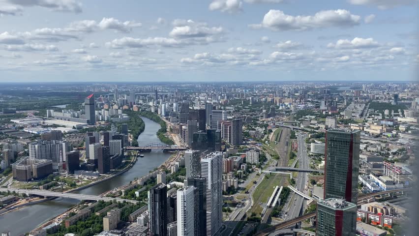 Vibrant skyline of Moscow features contemporary buildings and a winding river reflecting a bustling urban environment, captured on a sunny day.