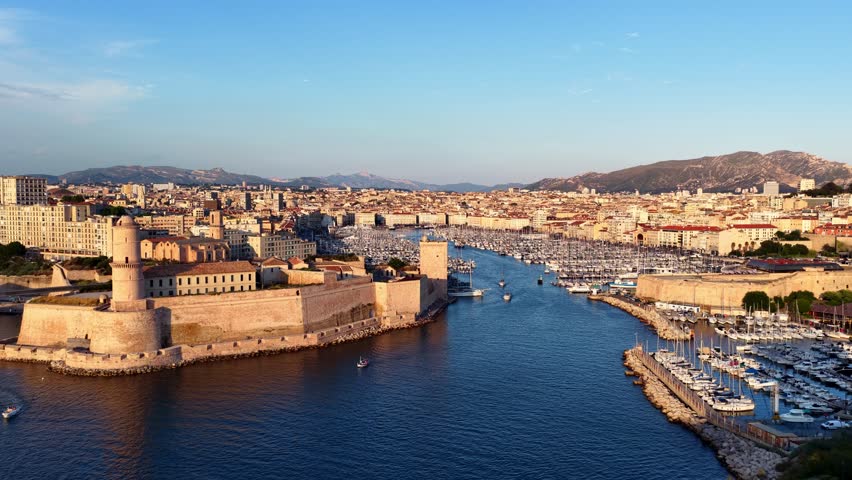 drone shot of Marseille old port, France, flying over historic fort and ships in the marina in French port of Marseille at sunset, fortress of Marseille 