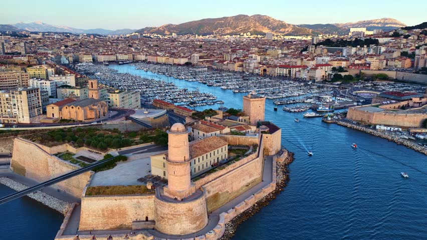 orbiting drone shot of Marseille old port, France, flying over historic fort and ships in the marina in French port of Marseille at sunset, fortress of Marseille . High quality 4k footage