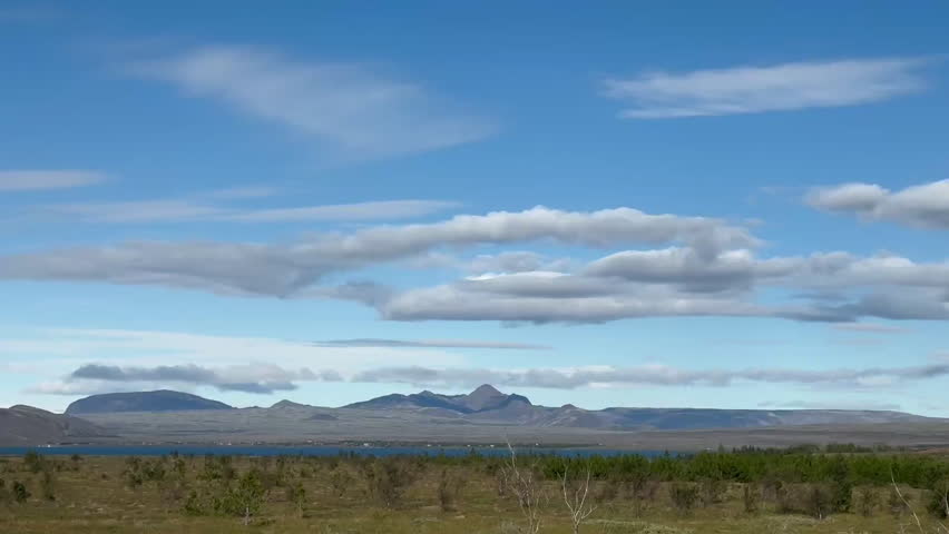A wide-angle view of a stunning natural landscape with mountains in the distance at Iceland, open fields, and a serene sky, tc01
