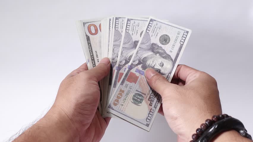 Holding a stack of crisp 100-dollar US currency notes, symbolizing wealth, financial transactions, or business prosperity in professional or personal contexts.