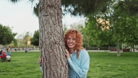 Redhead woman leaning against tree in park - Powered by Shutterstock - Get 15% off with code: PIKWIZARD15