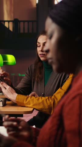Vertical Video African american woman asking people to keep quiet in the library, struggling to read a book due to noise and disrespect. Making a polite request for the library etiquette. Camera A.