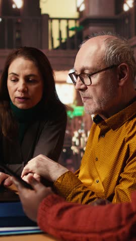 Vertical Video Mature academic colleagues prepare documents for university coursework or exams, transcribing essential ideas from textbooks. Research and education in a quiet public library. Camera A.