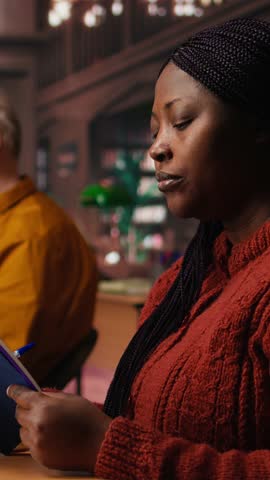 Vertical Video Focused woman in a study area reading and researching for master degree, reflecting the determined lifestyle of a student reaching academic and personal goals. Knowledge. Camera A.