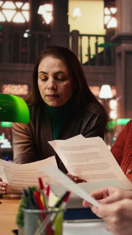 Vertical Video Cast members practicing script reading for a classic drama play in a library, showing dedication to acting and passion for character development. Theatrical arts role play. Camera A.