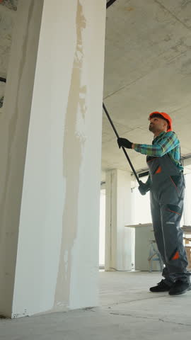 Construction worker priming walls in new building