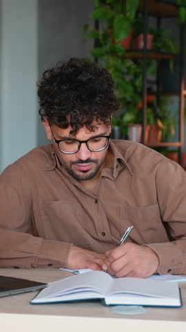 Focused employee taking notes and typing on laptop in modern office