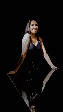 Fashionable woman enjoys spaghetti in a stylish studio setting at night