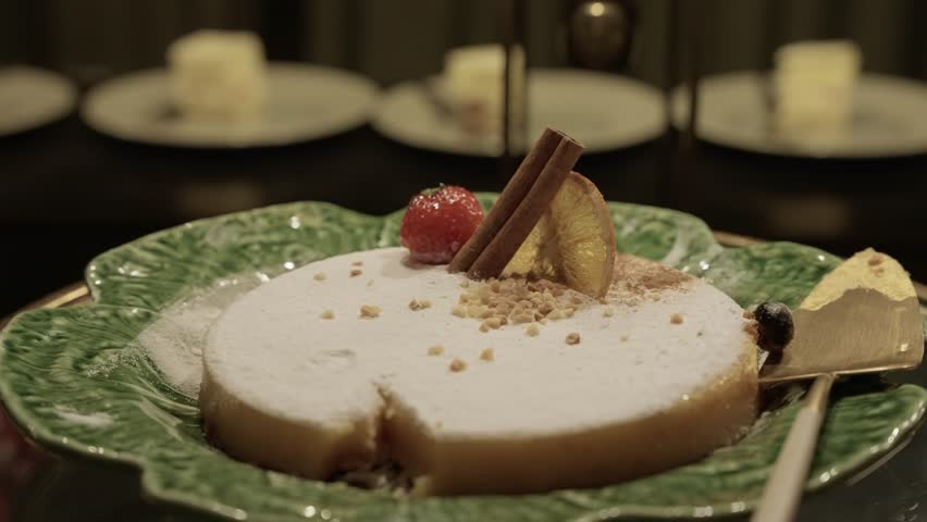 close up of elegant sliced cake with cinnamon and fruit garnish on a green ceramic plate