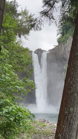 Snoqualmie Falls in Washington state flows into creek at the bottom on a cloudy summer day  