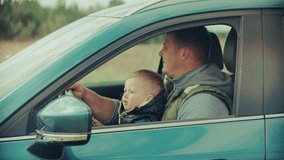 father and his young child in a car, with the child seemingly engaged with the steering wheel conveying themes of family, travel and early childhood curiosity. Family outing car journey father and son - Powered by Shutterstock - Get 15% off with code: PIKWIZARD15