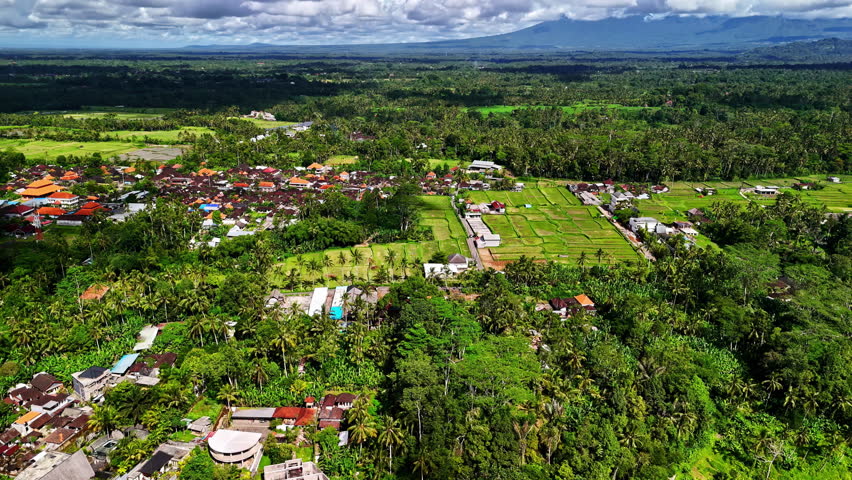 Aerial view of Ubud, Bali, featuring green rice fields, dense jungle, and vibrant village life in Indonesia's cultural heart
