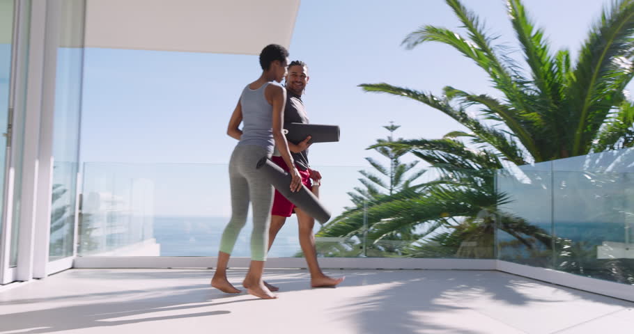Diverse fitness partners walking on ocean balcony placing mats then inhaling rhythmic breaths. Wellness, harmony, serenity, outdoors, activity, relaxation, mindfulness