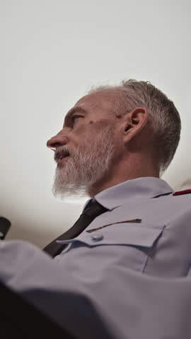 Vertical shot of male Caucasian military tactician in uniform speaking during conference, briefing plan indoors