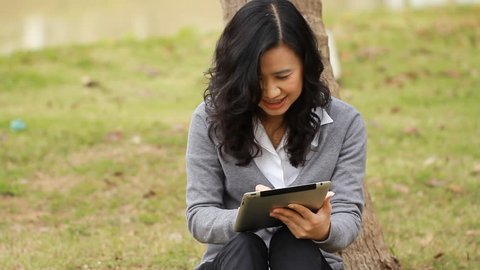 Woman surfing the web with electronic tablet in park