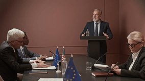 Stab shot of three international delegates in formal suits listening to mature Caucasian leader giving speech during conference in office - Powered by Shutterstock - Get 15% off with code: PIKWIZARD15