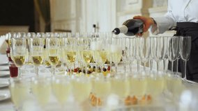 Buffet table at a festive event. An unrecognizable waiter pours champagne into glasses. Glasses with alcoholic drinks, champagne, wine and snacks for a social event, wedding, anniversary or birthday. - Powered by Shutterstock - Get 15% off with code: PIKWIZARD15