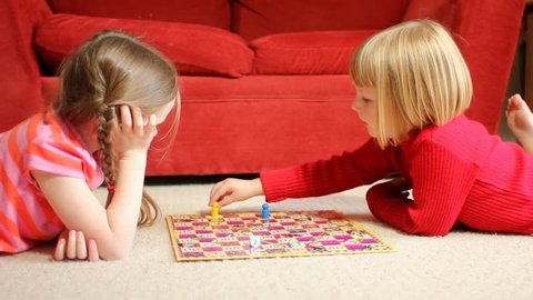 Two little girls playing a board game - lying on the floor
