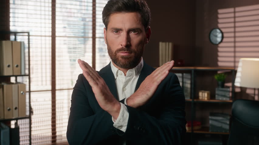 Confident serious angry Caucasian man male guy businessman business employer entrepreneur in office looking at camera crossed hands refuse deny forbid disagree reject no sign protest block protective