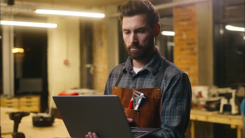 Caucasian wood master man typing laptop shopping app online in workshop builder handyman guy using Internet pc carpenter male buying goods artist architect browsing website small business cyberspace
