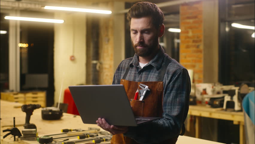 Caucasian wood master man typing laptop shopping app online in workshop builder handyman guy using Internet pc carpenter male buying goods artist architect browsing website small business cyberspace