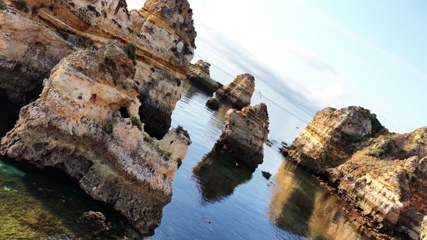 Explore the stunning rock formations along the coast of Algarve in Portugal during a serene afternoon