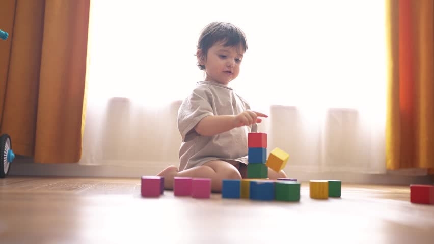 small child playing home. happy and full of joy childhood, children's dream concept. beautiful little girl sitting on lifestyle the floor and playing with colorful cubes