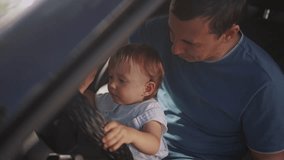dad plays with his son in car. people family and children concept. beautiful little kid sit and plays on his father's lap and turn the steering wheel lifestyle of his car - Powered by Shutterstock - Get 15% off with code: PIKWIZARD15