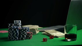 Stack of poker chips, dice, and money on table beside laptop, online casino - Powered by Shutterstock - Get 15% off with code: PIKWIZARD15