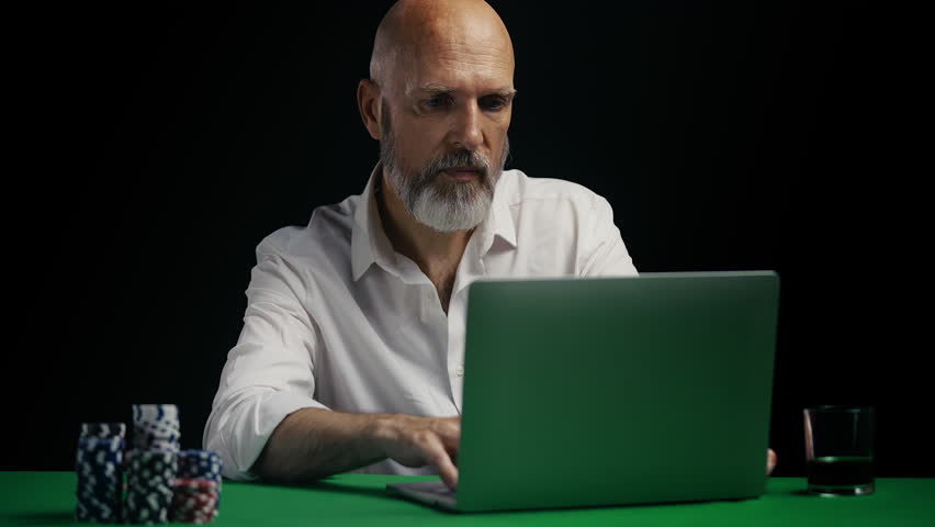 Middle-aged man betting online and winning poker game on laptop, gesturing yes