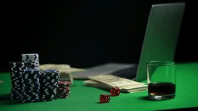 Dollars, poker chips, and dice on table near laptop, representing online casino - Powered by Shutterstock - Get 15% off with code: PIKWIZARD15