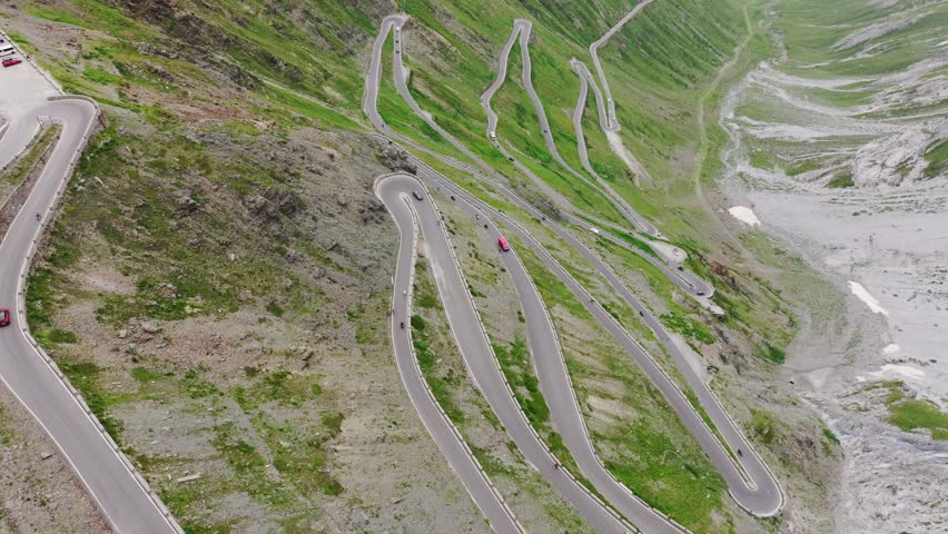 Curvy alpine pass with cars winding through Stelvio switchbacks in summer mist