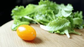 Chef cuts a tomato in half on a wooden board on a black background. Close-up of tomatoes and lettuce. Concept of healthy eating and organic farm products. 4k footage. - Powered by Shutterstock - Get 15% off with code: PIKWIZARD15