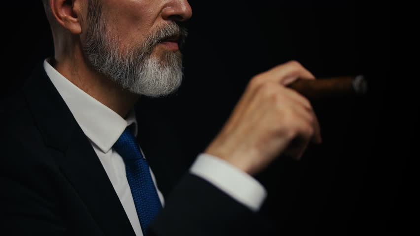 Close-up of middle-aged male boss smoking cigar, symbol of power and success