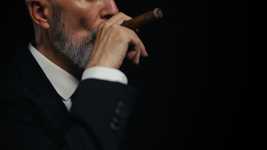 Close-up of middle-aged male boss smoking cigar, symbol of power and success