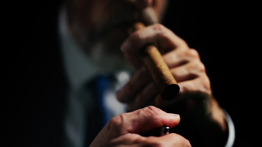 Close-up of man in business suit lighting cigar, enjoying the act of smoking
