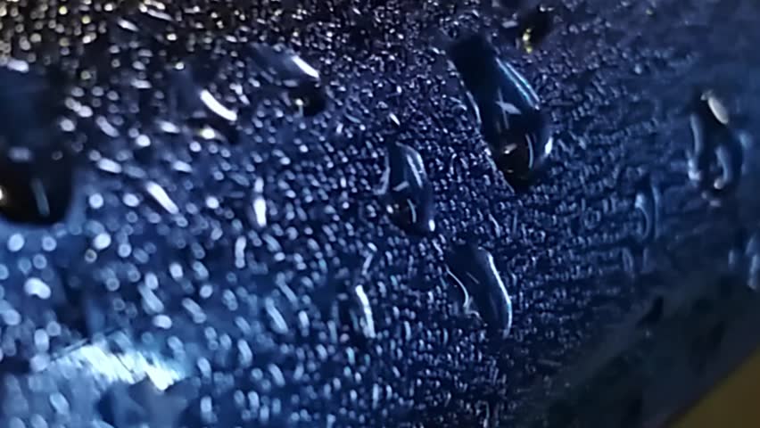 Wet surface with water droplets on it. The surface appears to be a metal object, possibly a car or a piece of machinery. The water droplets are scattered across the surface