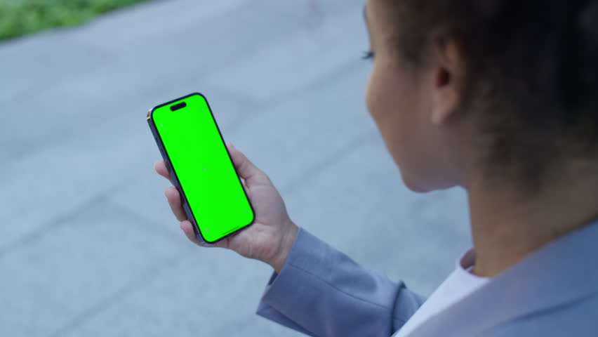 Woman holding smartphone with green screen display