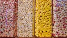 Close-up view of colorful candies neatly sorted into four vertical transparent containers. The sweets include pink, yellow, white, and mixed pastel colors, creating a vibrant and inviting visual - Powered by Shutterstock - Get 15% off with code: PIKWIZARD15