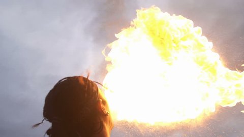 Young man firebreathing against the sky - super slow motion