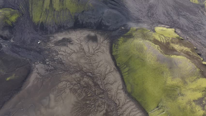 Aerial view of a landscape with a riverbed carving through mossy terrain, the textures create a visual contrast, highlands, Iceland.