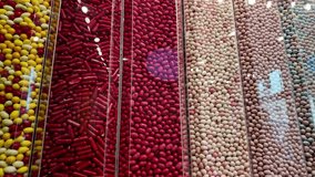 A vibrant assortment of colorful candies neatly arranged in transparent vertical tubes on a wall display inside a candy store. The image showcases a wide variety of textures and hues, including red - Powered by Shutterstock - Get 15% off with code: PIKWIZARD15