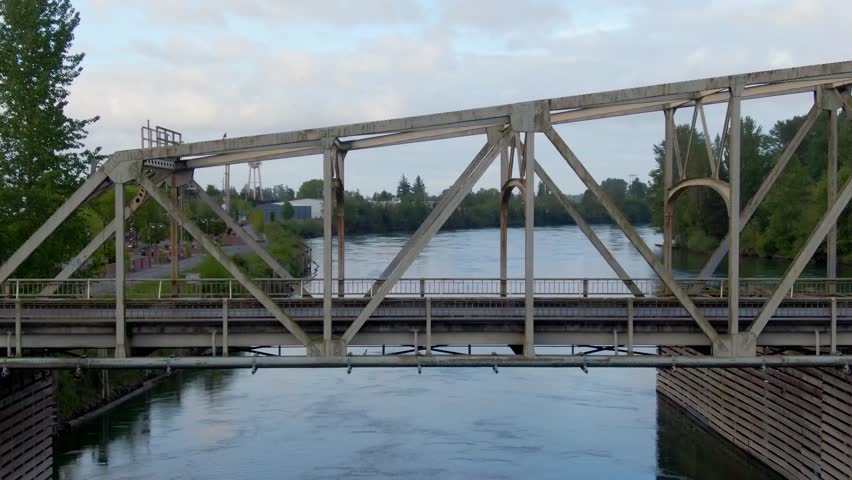 Metal, Arched Bridge by an Idyllic Small USA Town. Mount Vernon, WA. In Skagit Valley, Washington. Close up to Medium with driving cars and birds, during the Tulip Festival. Pull out.