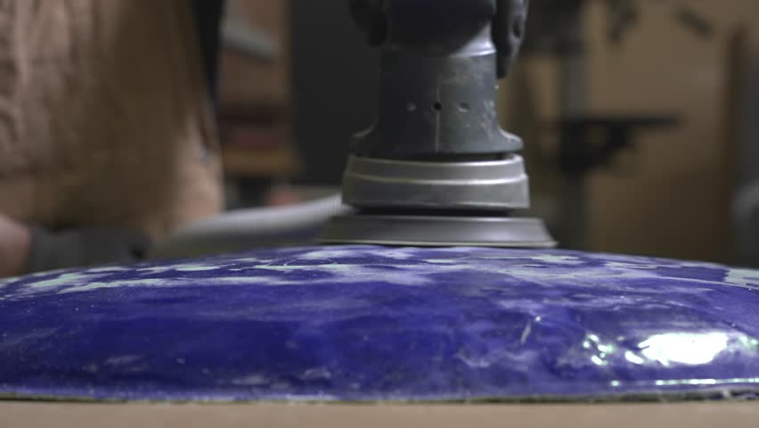 A worker grinds and polishes cured epoxy resin that has turned into carbon fiber