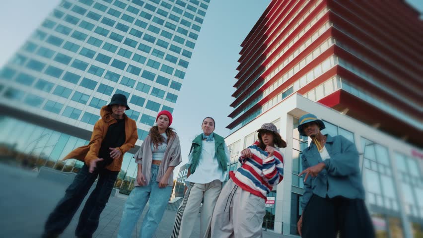 Urban dance crew performing dynamic choreography against modern skyscraper backdrop, showcasing energetic moves blending street style with contemporary artistic expression