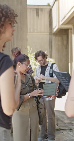 A group of diverse students actively participating in an outdoor education session led by their female teacher. They are engaged in learning and discovery on a university campus.