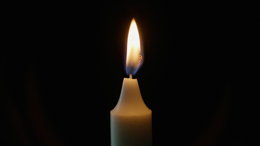 Fingers squeezing candle fire on black background closeup. Unrecognizable person snuffing out wax lights against dim studio wall. Unknown figure reaching toward glowing fire indoors. Evening scene